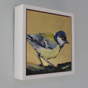 a framed Jill Hudson painting of a yellow and blue bird on a tree branch against a gold background 