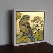 a framed Jill Hudson painting of a yellow and purple bird in a yellow flowering tree  against a gold background.