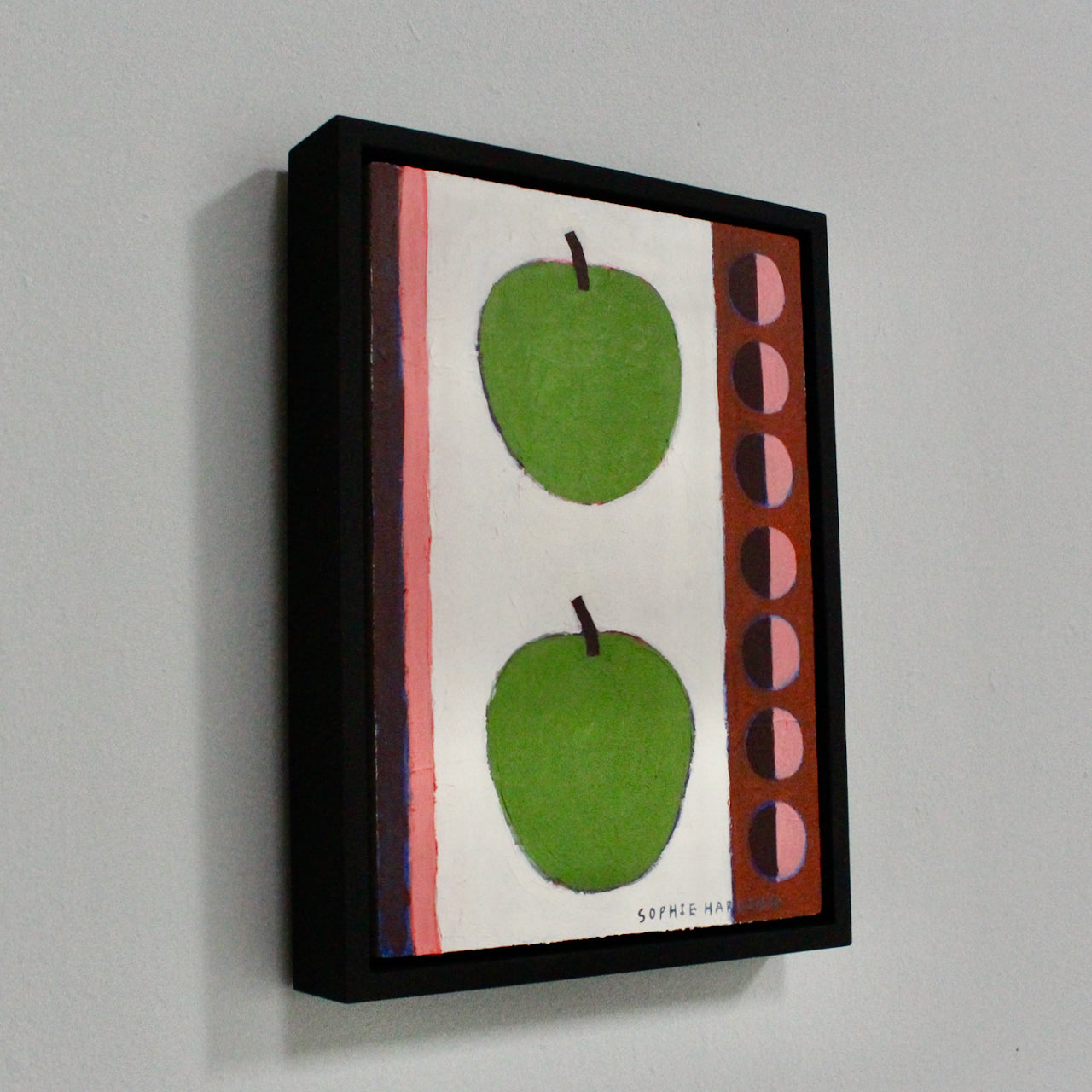 a framed painting by Cornwall artist Sophie Harding of two green apples with a pink decorative border to either side.