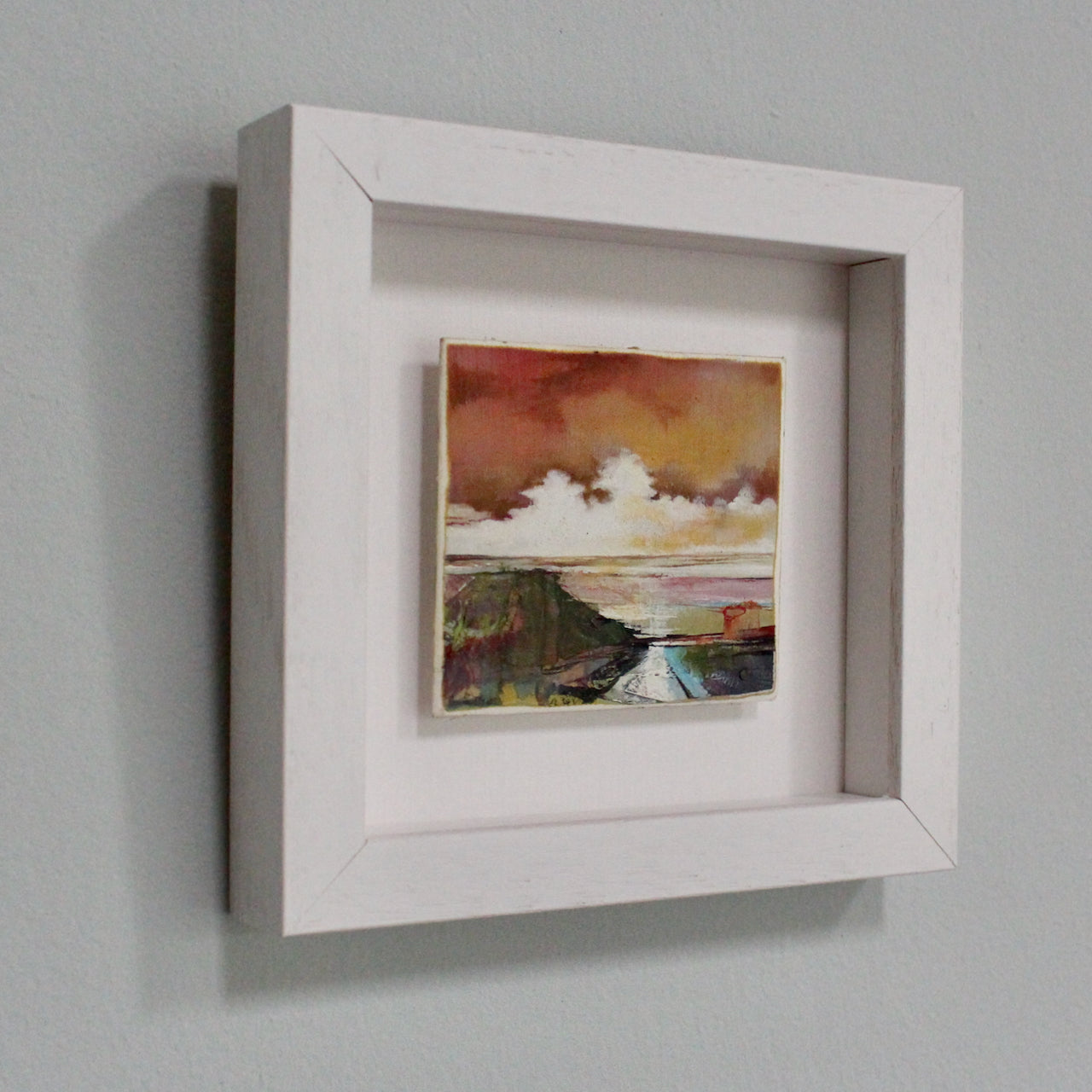 a small framed painting of a beach scene at sunset with pink sky and dark seashore by artist Julie Ellis 