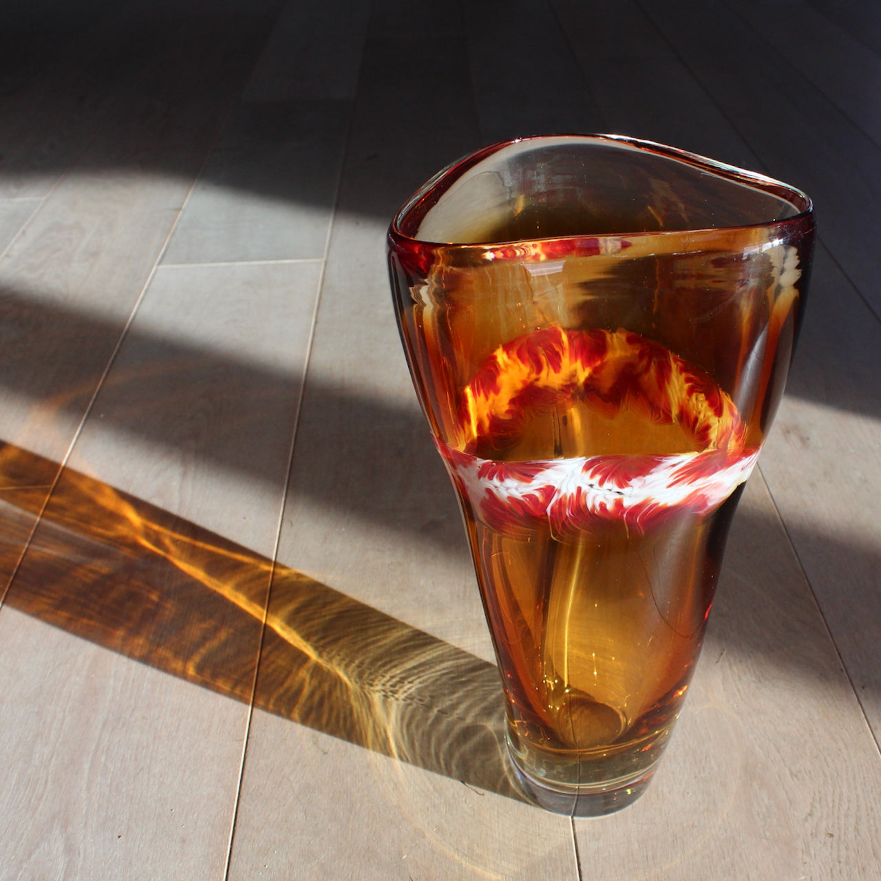 Benjamin Lintell hand-blown glass vessel in amber with a white and red murani detail midway up, it was designed and made by Benjamin in Murano, the glass capital of the world