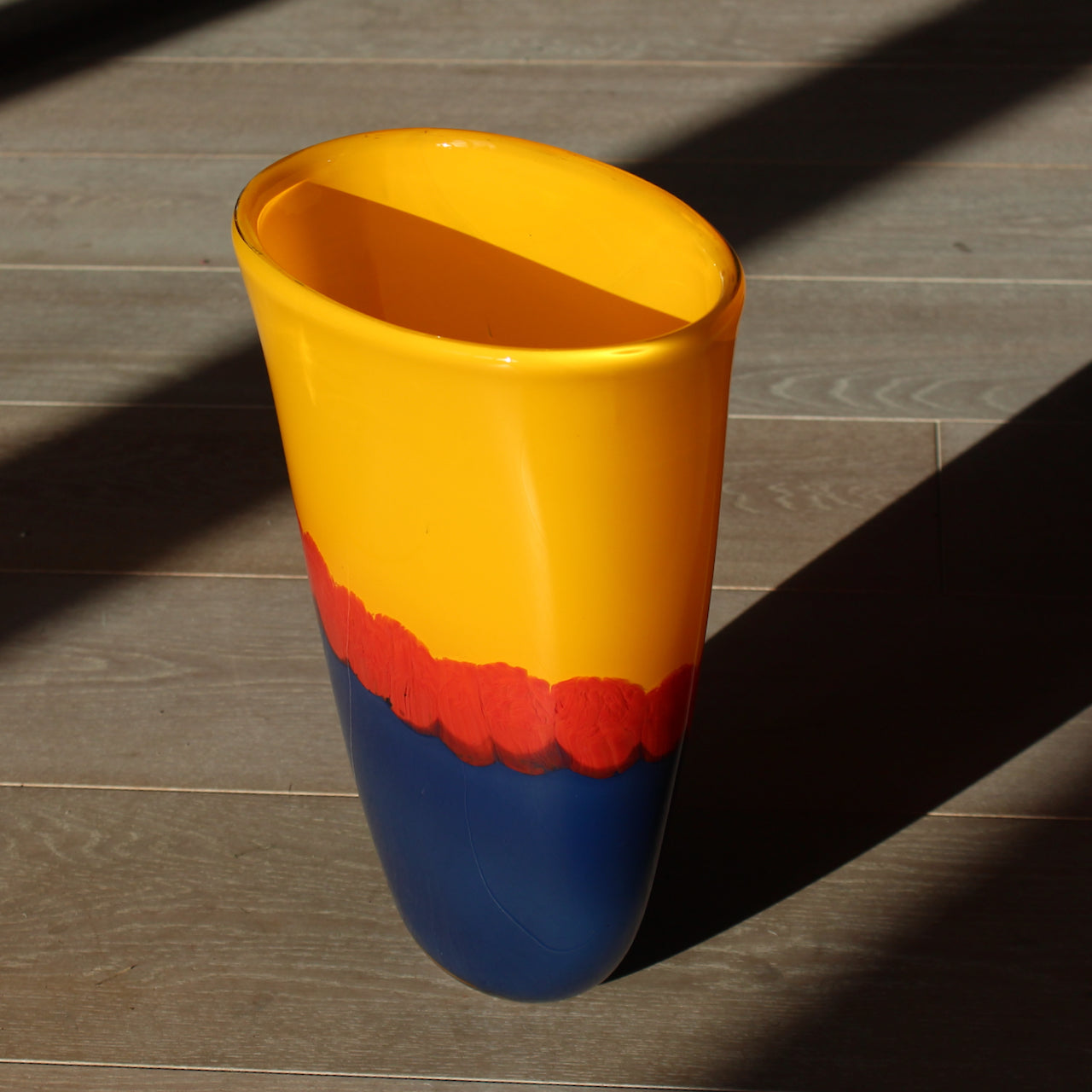 A Benjamin Lintell glass vessel in orange and blue with red detail midway down.