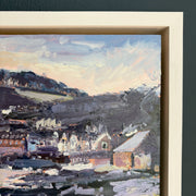 details of a framed painting of a village landscape with houses and hills.