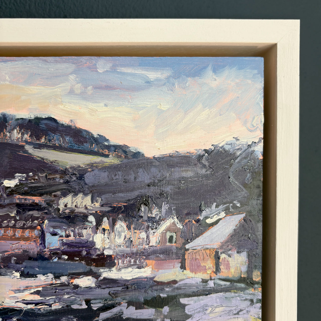 details of a framed painting of a village landscape with houses and hills.