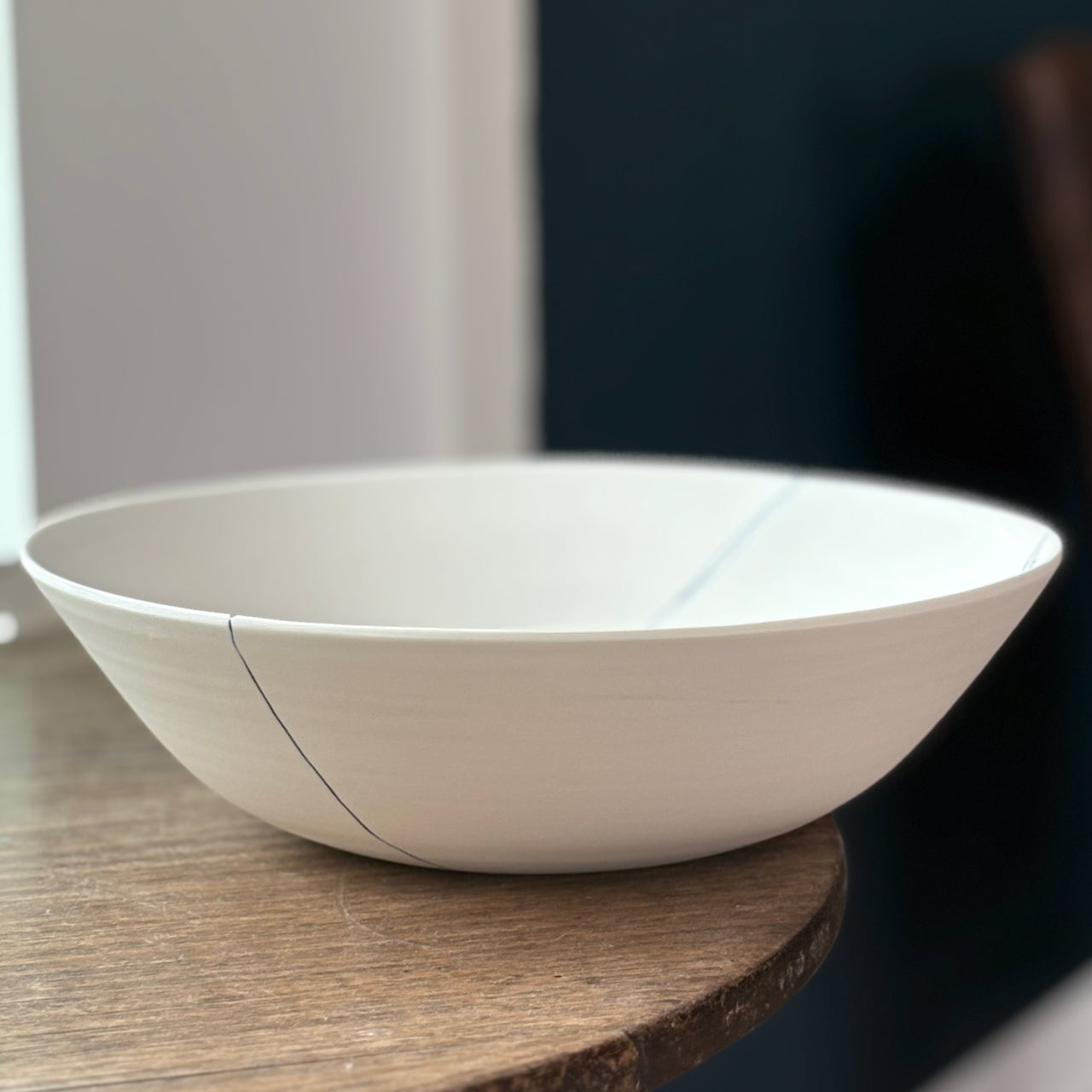 White ceramic bowl on a wooden surface with a blurred background