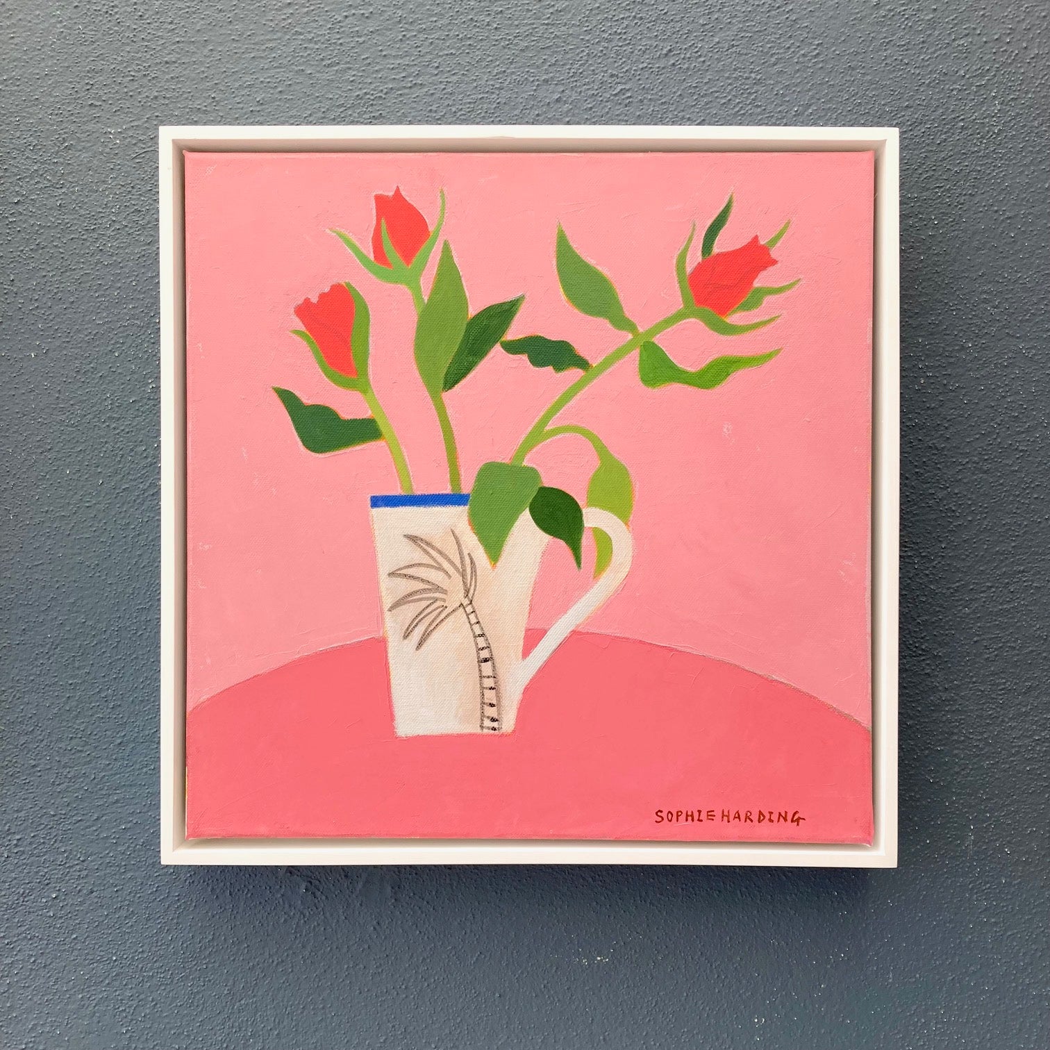 Framed artwork of a mug with red flowers on a pink background, signed 'Sophie Harding'.