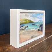 A Jill Hudson painting of Rame Head in Cornwall with a golden beach, dark rocks and green headland 