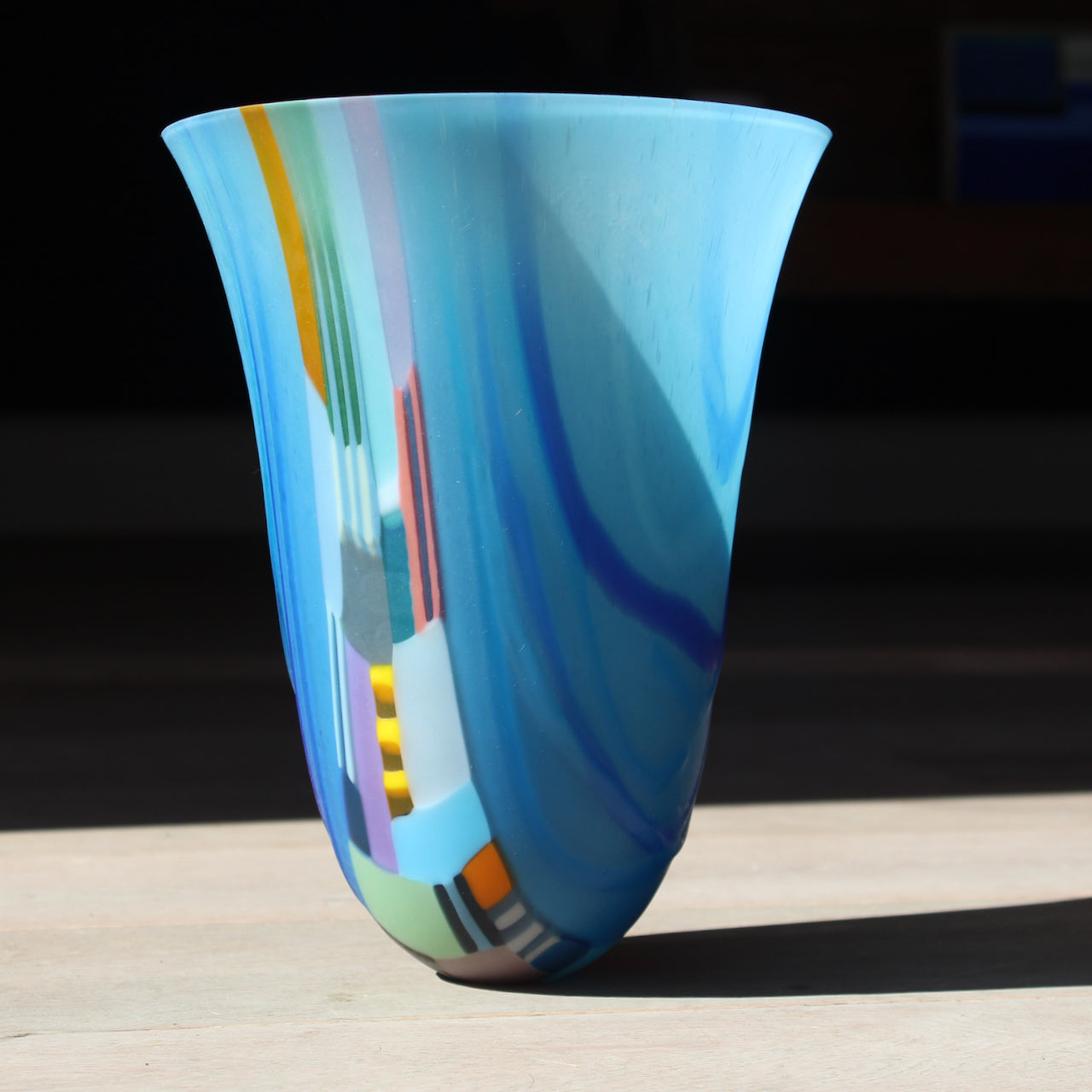 A large blue vessel with multicoloured detail in the centre by welsh glass artist, Ruth Shelley