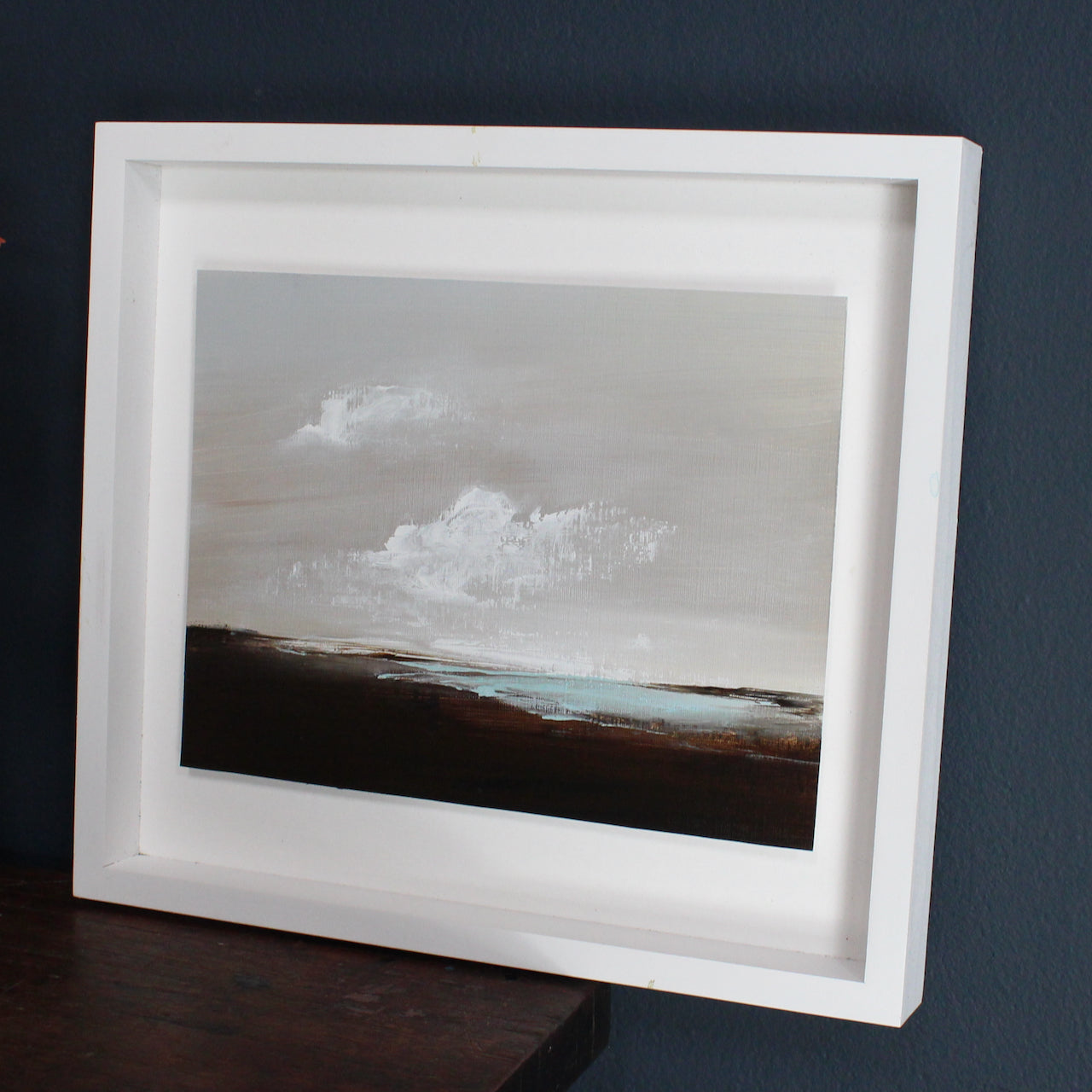 Artist Nicola Mosley, Seascape of dark shore with blue sea and white clouds