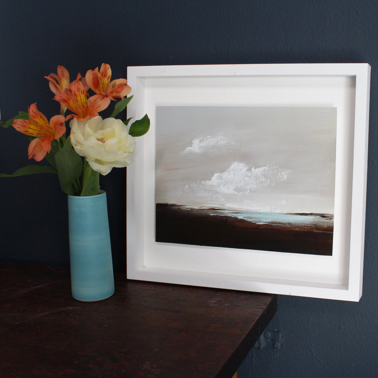 Artist Nicola Mosley, Seascape of dark shore with blue sea and white clouds.
