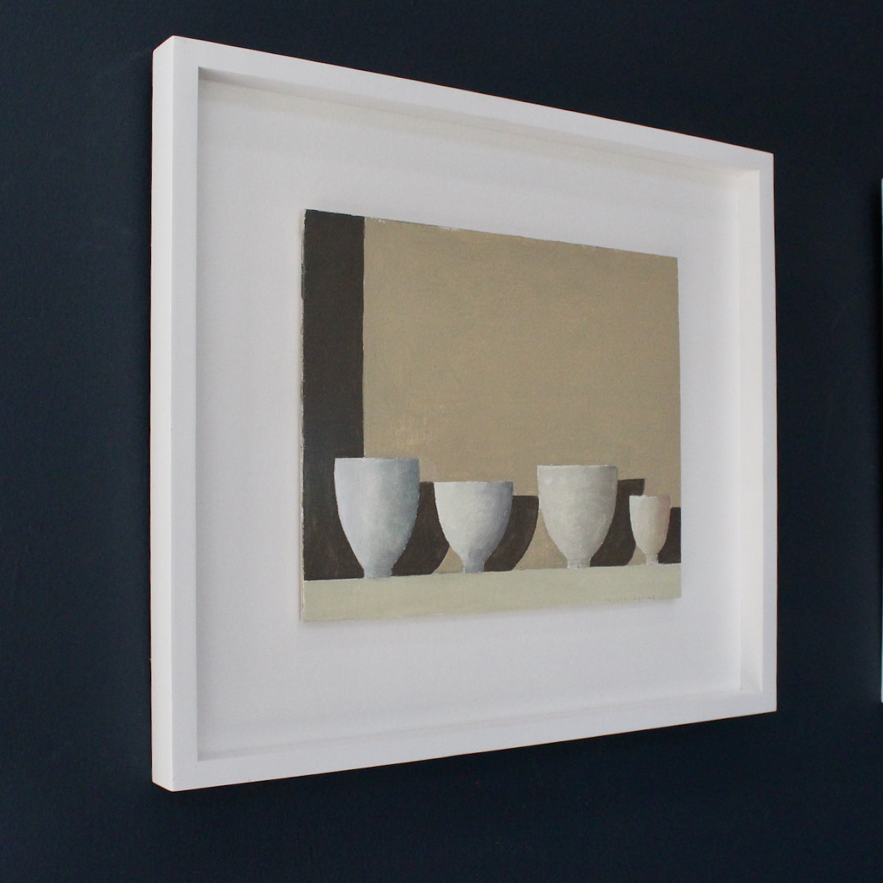 UK artist Philip Lyons framed painting of four white bowls with shadow against a taupe wall.