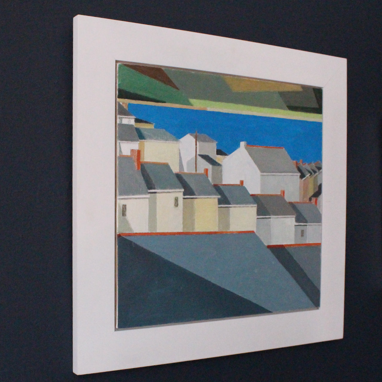 Artist Philip Lyons , framed painting of view of grey terraced roof tops with blue sea and coastline in distance.