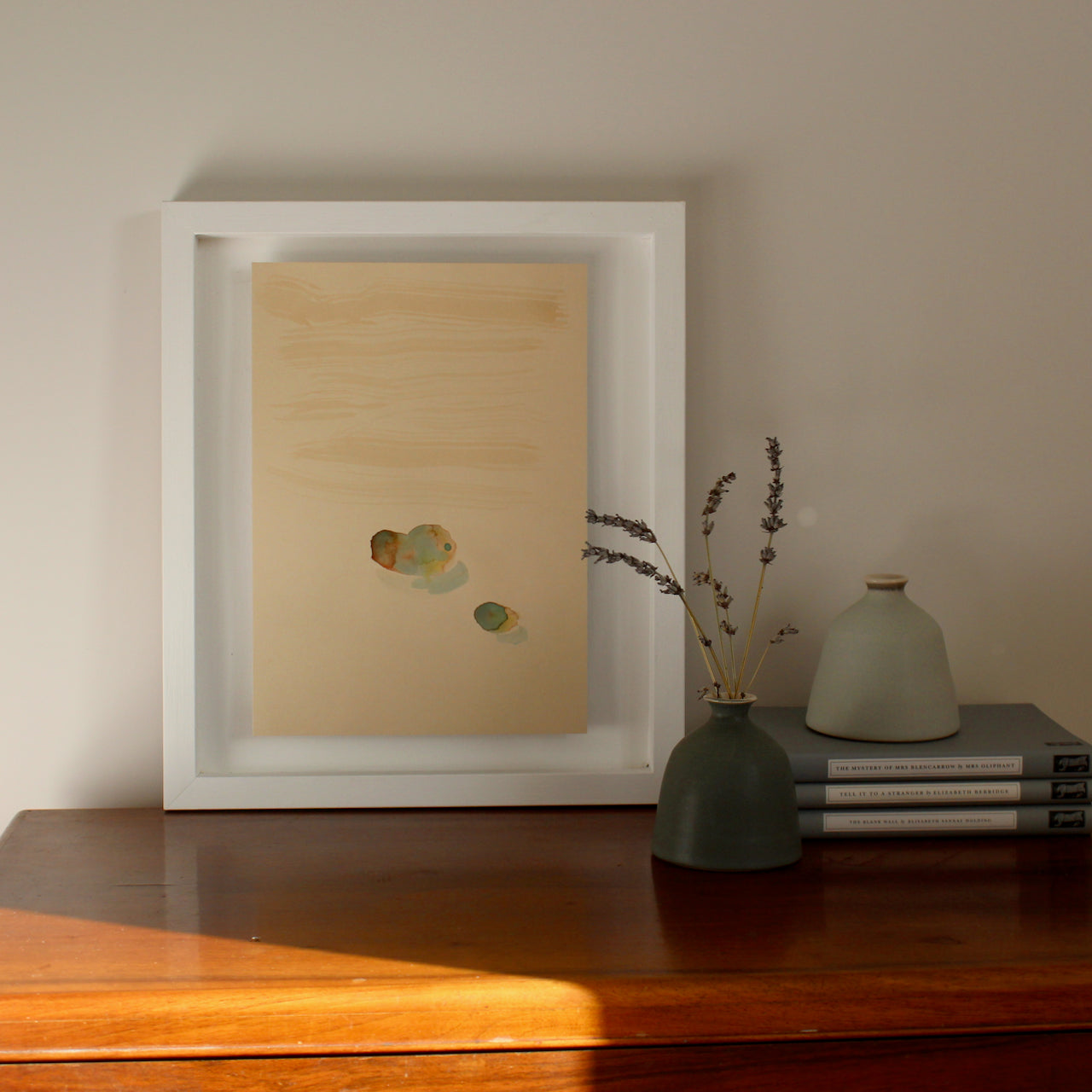 Tara Leaver abstract watercolour in white frame on top of wooden table next to two small ceramic green pots by EOT ceramics 