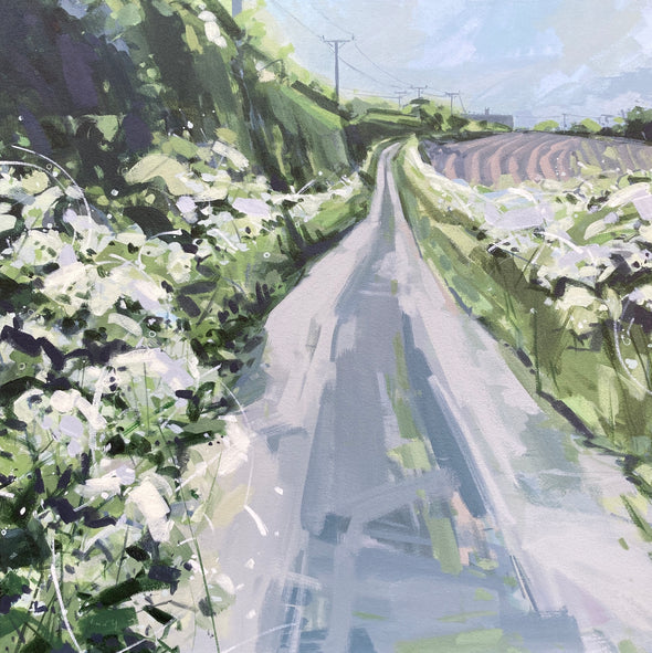 Grey road leading into the distance with green hedgerow and ploughed fields to either side by Cornish artist Imogen Bone