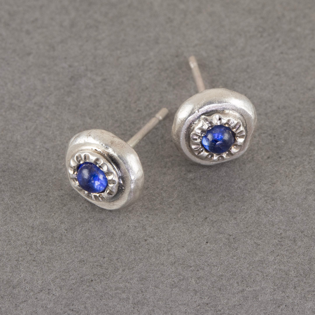 a pair of carin lindberg small silver stud earrings with blue sapphire stone.