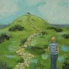 A figure in a stripy blue and white top walking towards a building on top of a hill with a footpath leading to the building by Cornish artist Siobhan Purdy