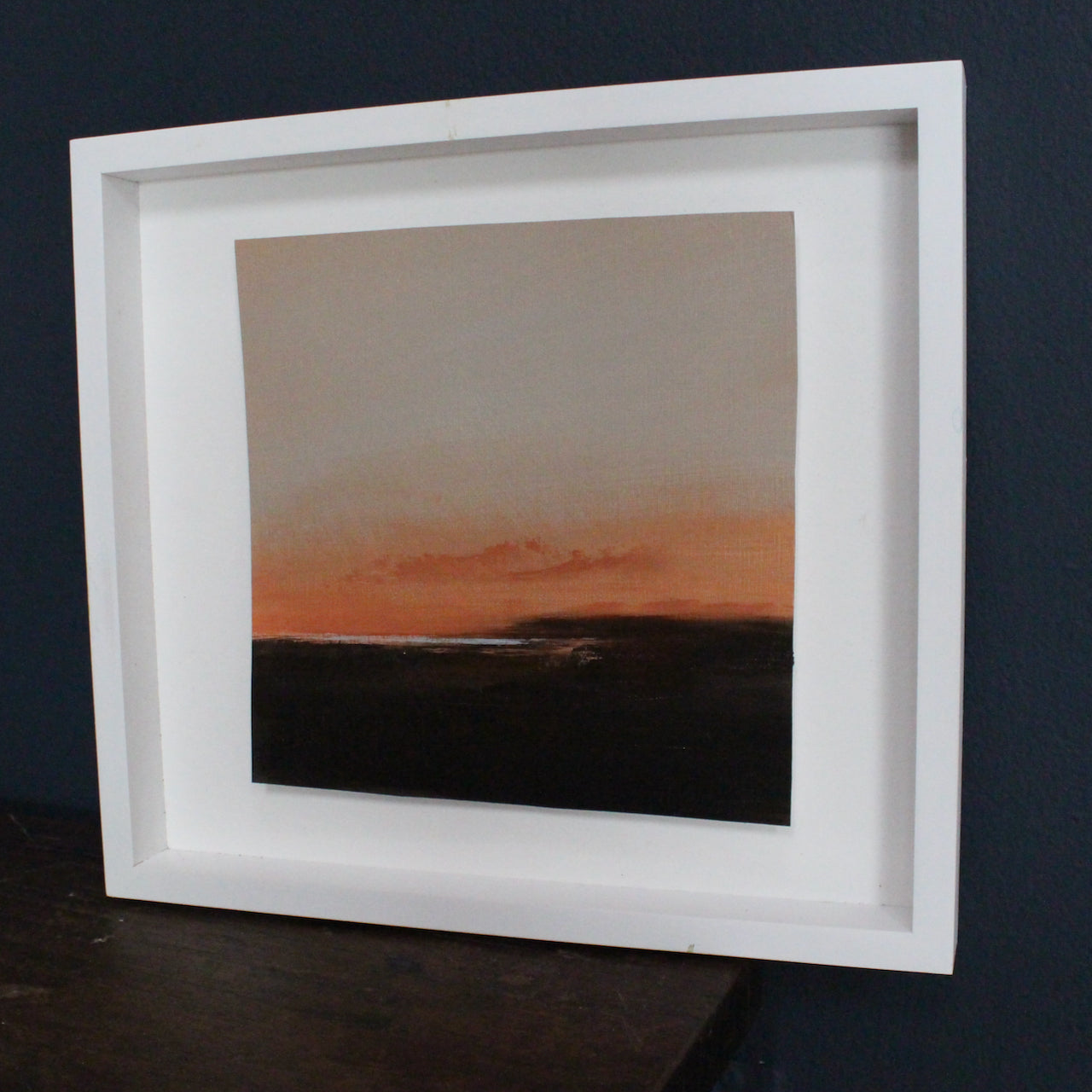 Dark headland with shimmering sea and dusk pink tone sky by artist Nicola Mosley.