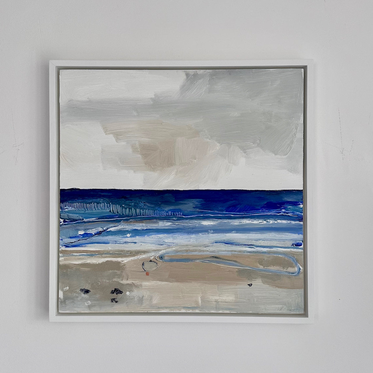 Seascape painting of shoreline with tones of blue sea, sand in foreground and light sky by Aimee Willcock.