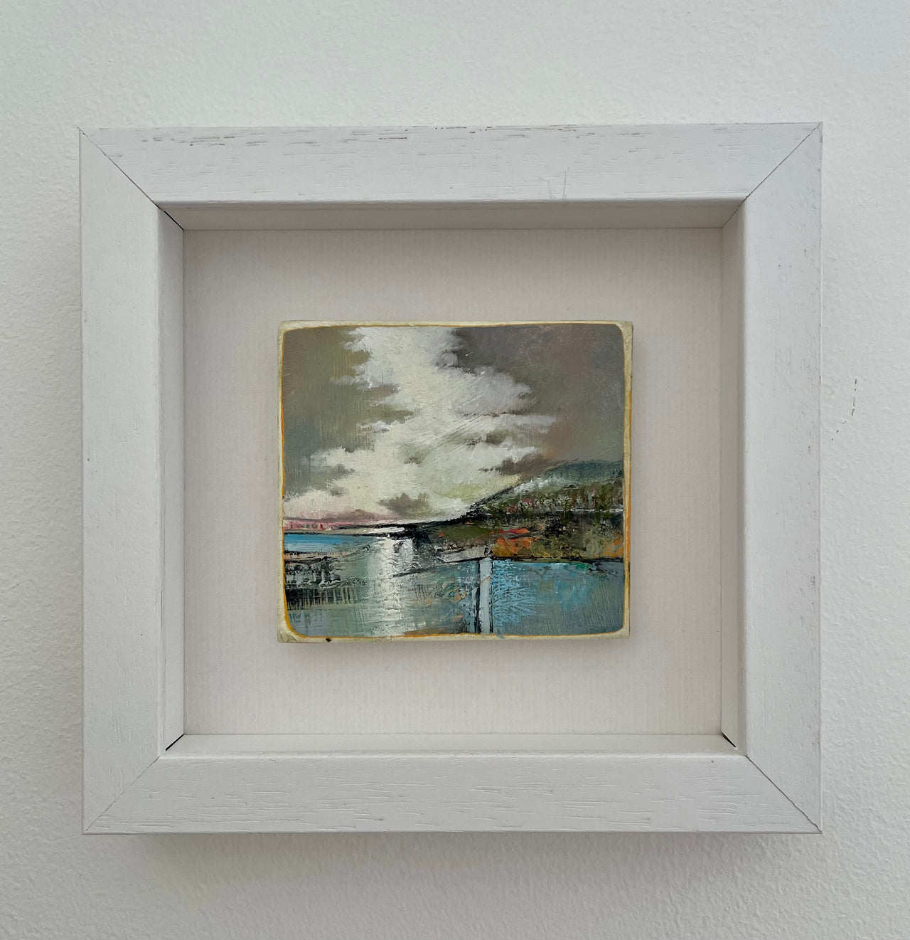 A Julie Ellis small framed painting of a headland against a grey and lilac sky and a pale blue sea.