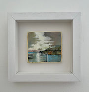 A Julie Ellis small framed painting of a headland against a grey and lilac sky and a pale blue sea.