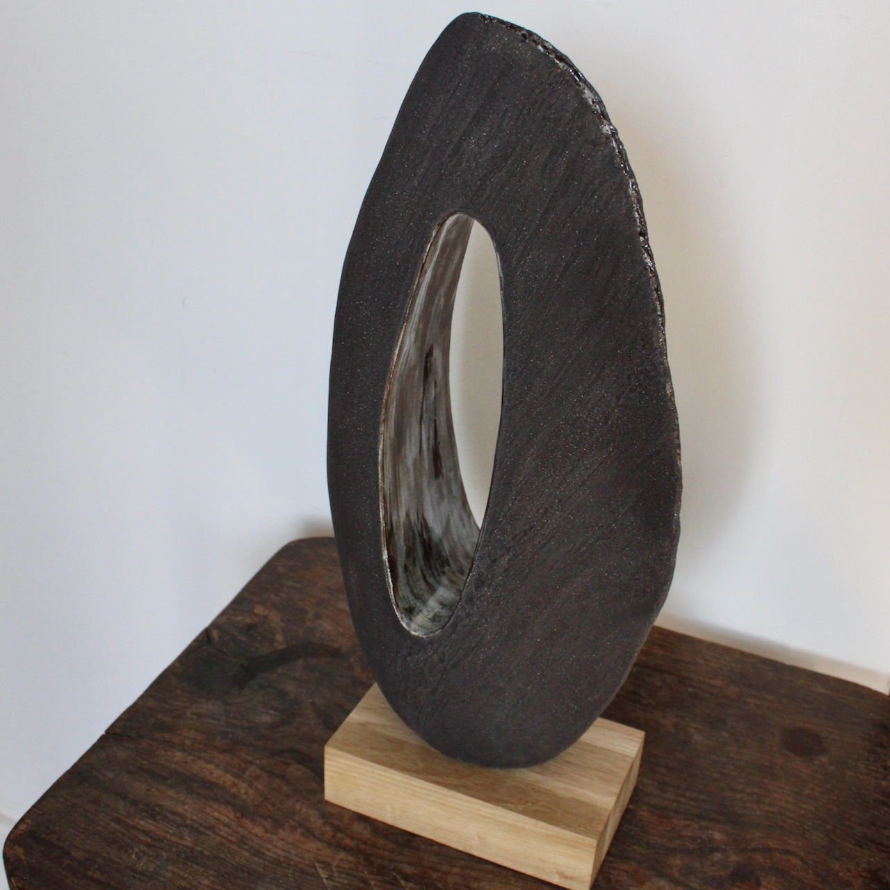 Cornish artist Anthea Bowen brown oval shaped sculpture with hollow centre on an oak stand