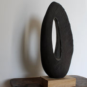 Anthea Bowen Cornish artist brown oval shaped sculpture with hollow centre on an oak stand.