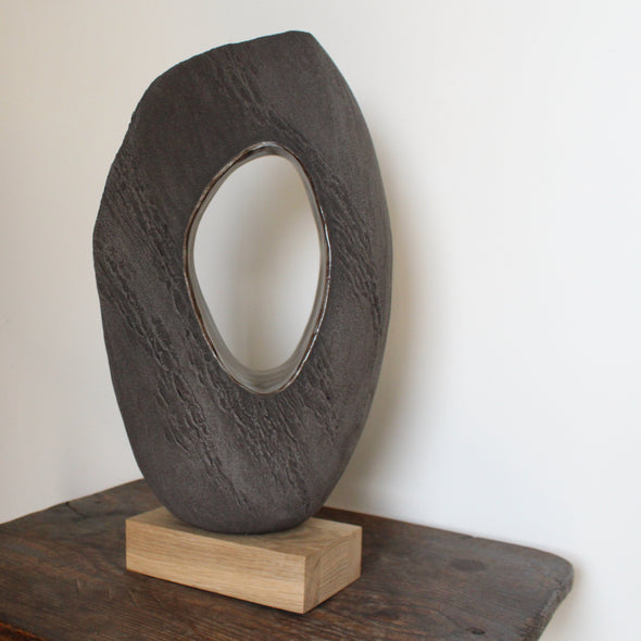Anthea Bowen brown oval shaped sculpture with hollow centre on an oak stand