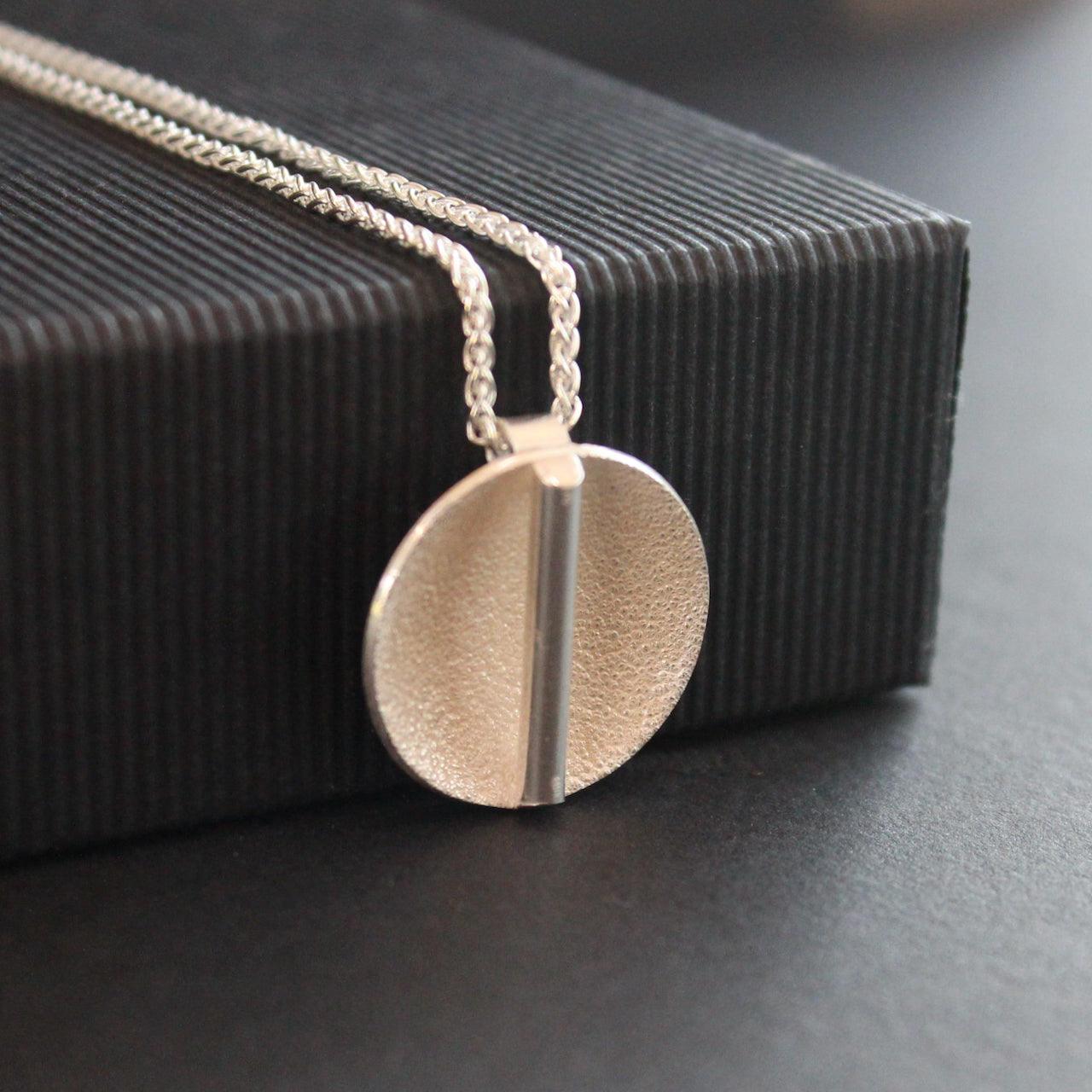 textured silver disc pendant with a central bar by Uk jewellery designer Beverly Bartlett