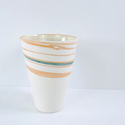 Ceramic cup with orange and blue stripes on a white background by Deborah Greenwood
