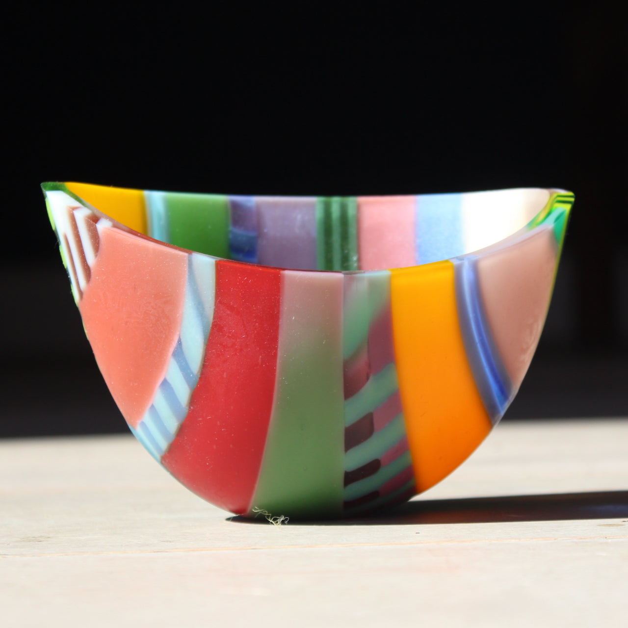 Beautiful vibrant glass bowl by artist Ruth Shelley in tones of pink, green, yellow, blue, red.