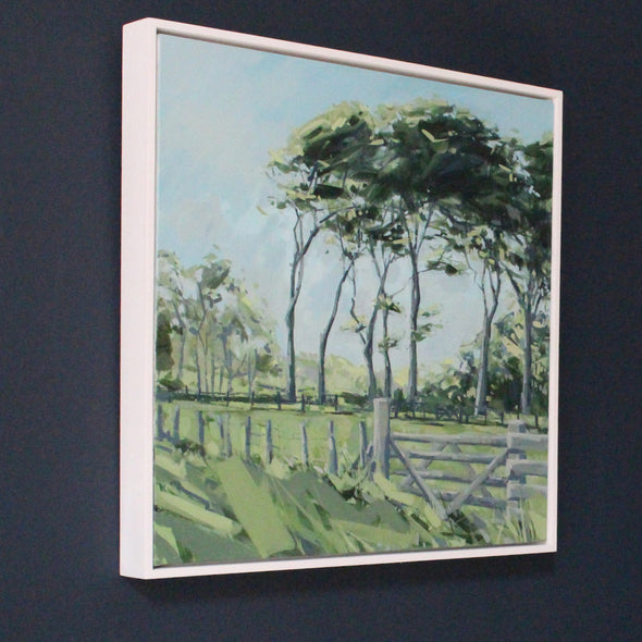 framed painting of Green field with fence and gate with tall green trees in the background on blue sky by Cornish artist Imogen Bone
