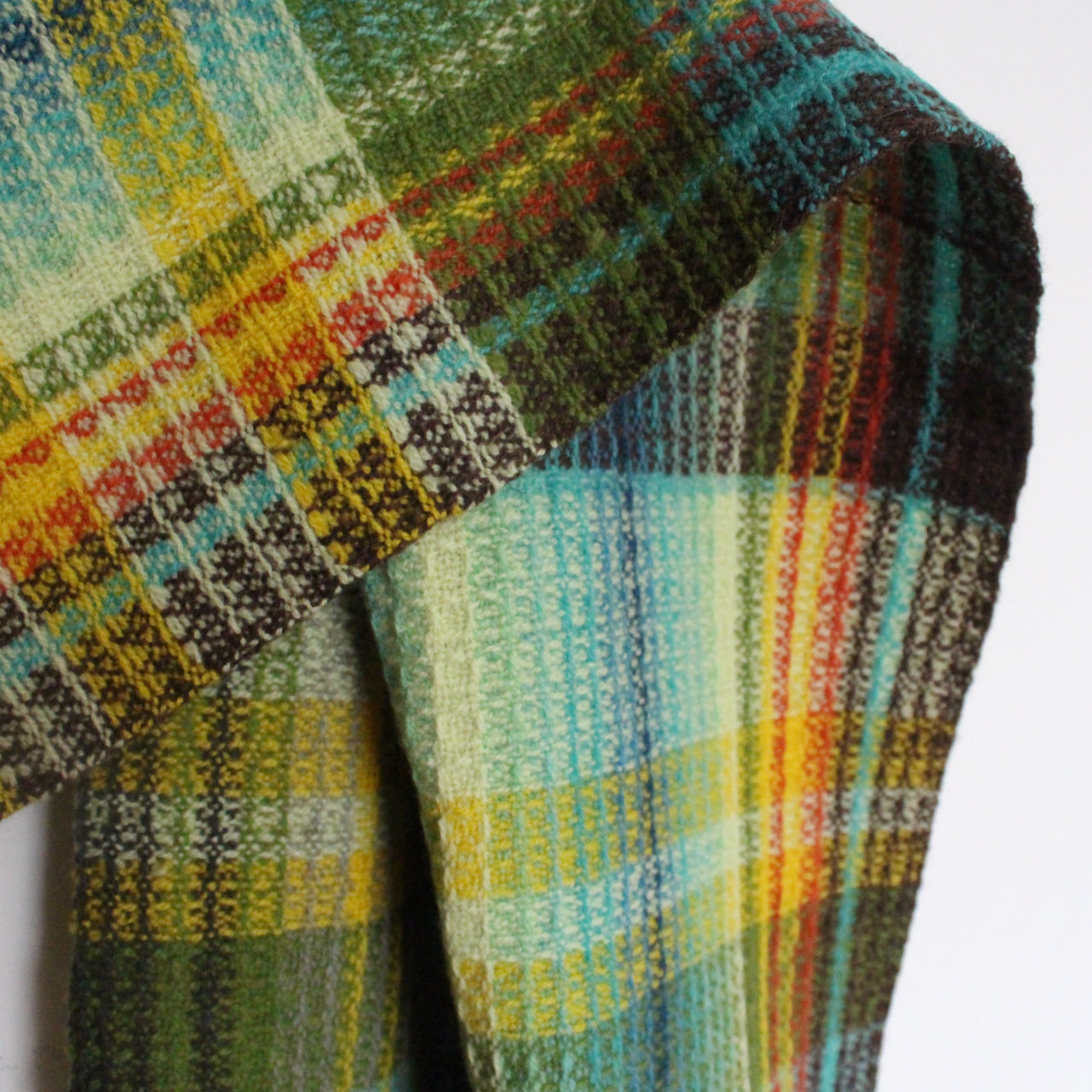 close up detail of  woollen hand-woven scarf in greens, yellow and black by Cornish textile artist Teresa Dunne