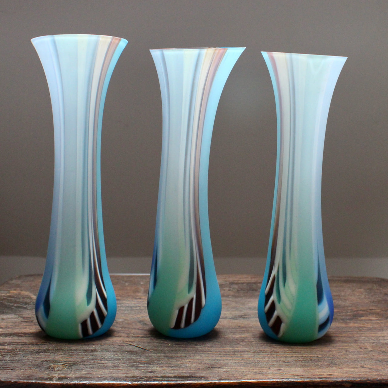 three multi-coloured glass vases on a wooden table