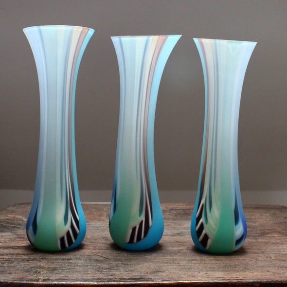 a group of three tall, slim multi-coloured glass vases with slightly angled tops made by glass artist Ruth Shelley 