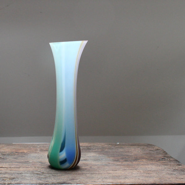 a tall, slim multi-coloured glass vase with a slightly angled top made by glass artist Ruth Shelley.