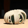 a small rounded stoneware sculpture hand carved with a pale green interior glaze by British ceramicist Michele Bianco 