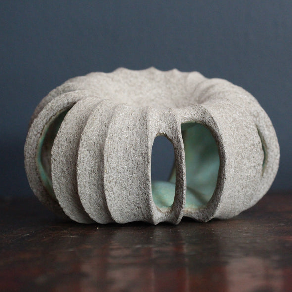 a small rounded stoneware sculpture hand carved with a pale green interior glaze by ceramicist Michele Bianco 