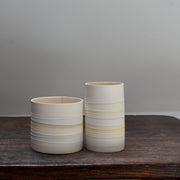 two white ceramic vases with pale yellow stripes 