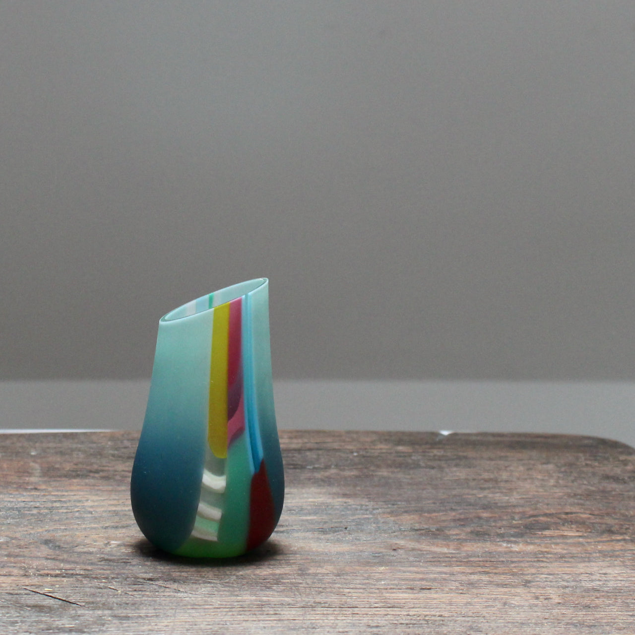 small glass vase in blue, green and pink with an angled top made by glass artist Ruth Shelley