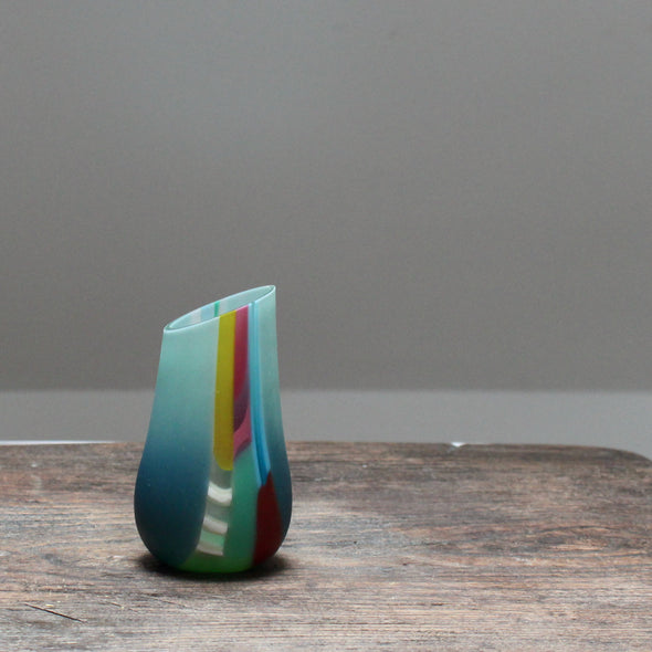 small glass vase in blue, green and pink with an angled top made by glass artist Ruth Shelley