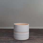 white ceramic pot with pale orange interior and grey stripes on the outside