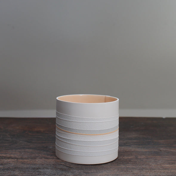 white ceramic pot with pale orange interior and grey stripes on the outside