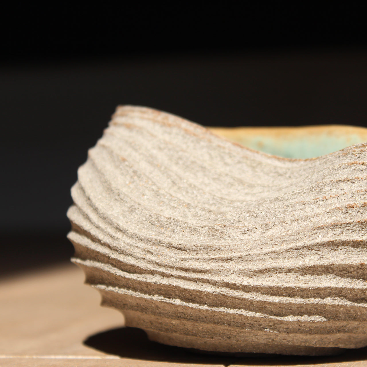 a stoneware bowl which has been hand carved to create a slumped and ribbed effect on the exterior with a pale green glaze inside it was made by UK ceramic artist Michele Bianco