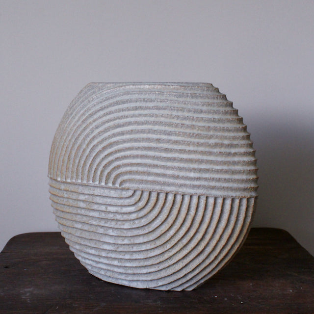 A large white  stoneware ceramic disc shaped vessel with carving detail by Michele Bianco.