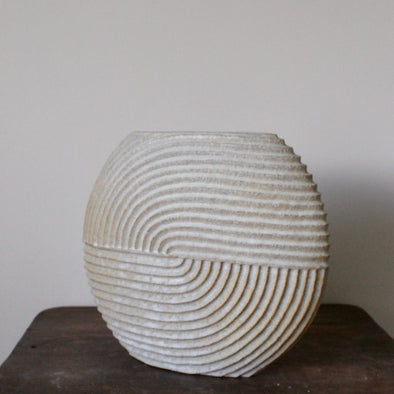 white  stoneware ceramic disc shaped vessel with carving detail by Michele Bianco pictured on a dark wood table