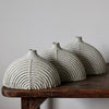 a collection of three rounded and carved pale grey stoneware bottles by Michele Bianco.