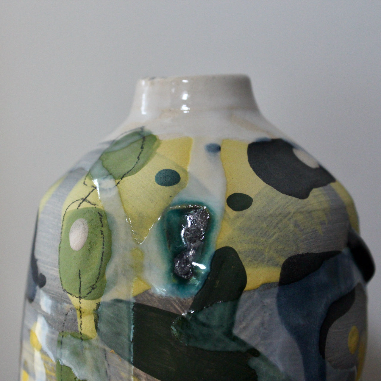 close up detail of a ceramic bottle in yellow, green and blue by ceramicist Dawn Hajittofi