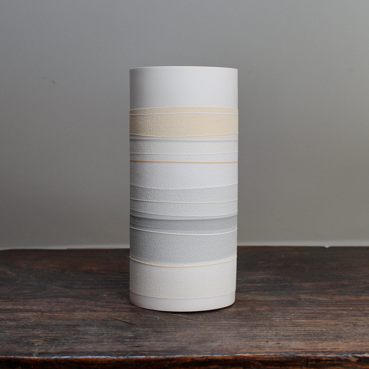 white ceramic cylinder vase with pale orange and grey stripes