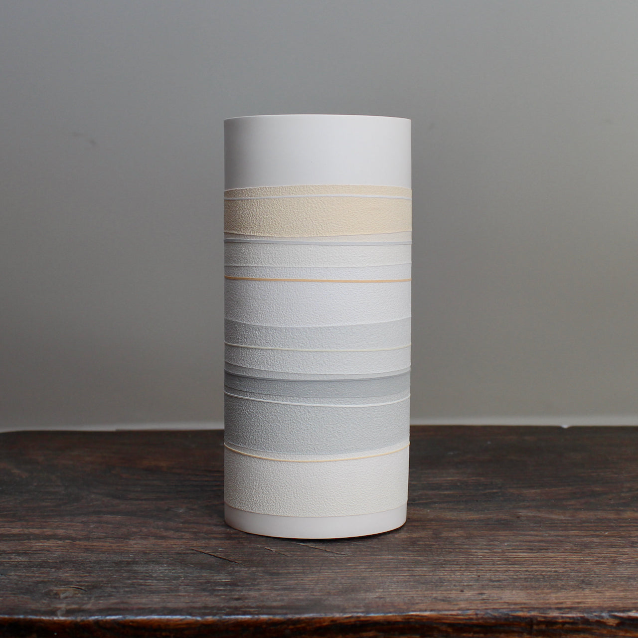 white ceramic cylinder vase with pale orange and grey stripes 
