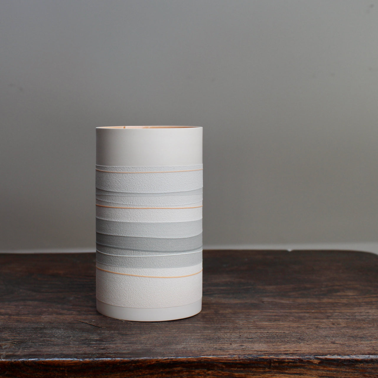 white ceramic vase with pale orange and grey stripes 